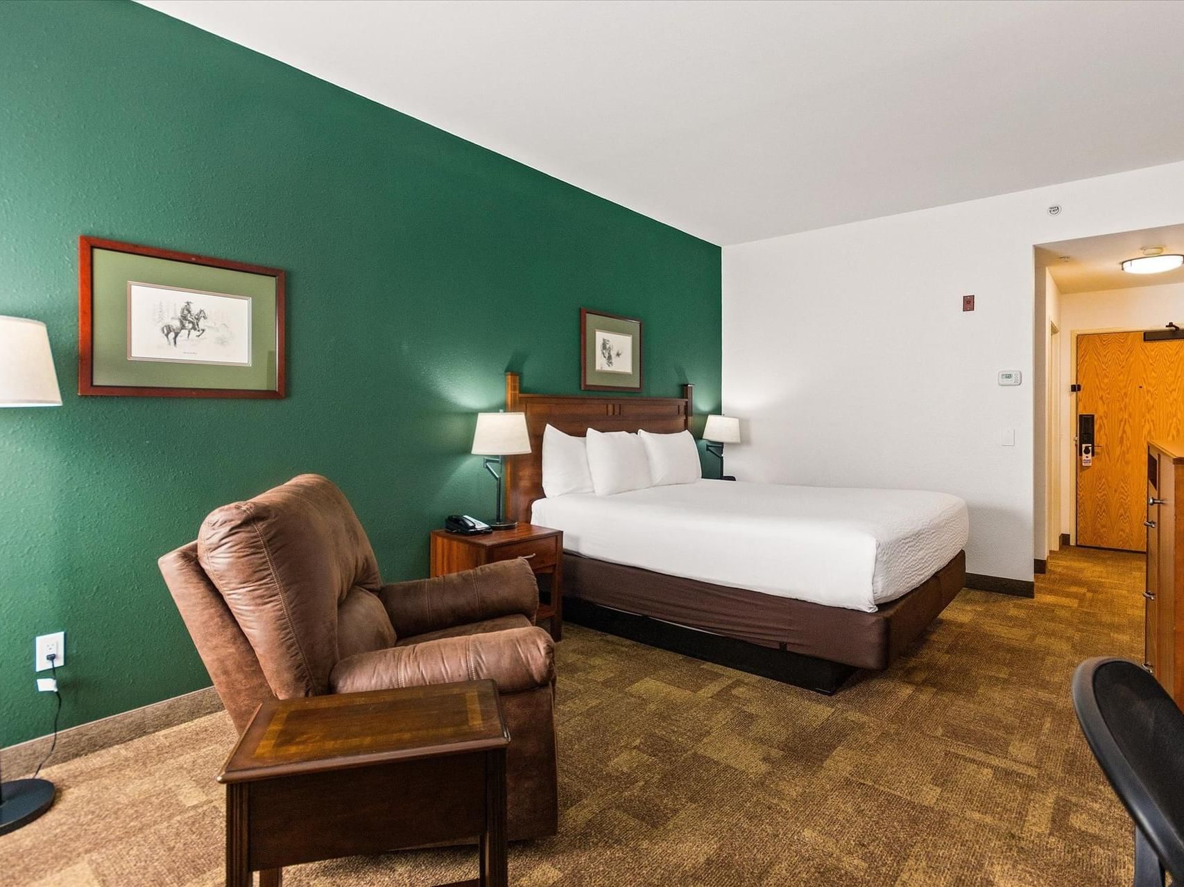 King bed, nightstands & cozy chair in Executive King at Boothill Inn & Suites