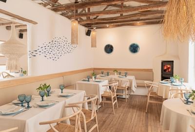 Naous Aegean Bistro with blue glasses by a fish mural under wood beams at 5Q House Chapinero
