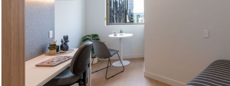 Studio Apartment at UniLodge Brisbane City with desk, chairs, and bed.