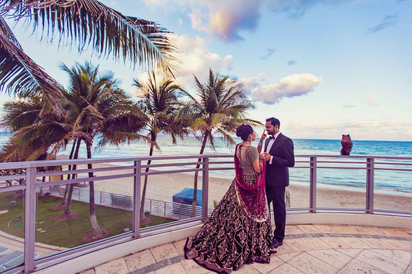 Couple in formal attire on a beachfront balcony at sunset at Diplomat Beach Resort