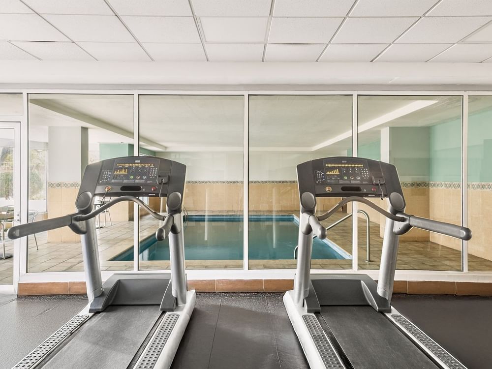 Dos cintas de correr modernas en el gimnasio de Fiesta Inn Express Nuevo Laredo con vista a la piscina