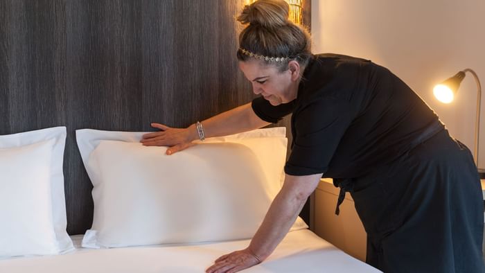 A Woman preparing a Standard Double bed at Hotel d'Alsace