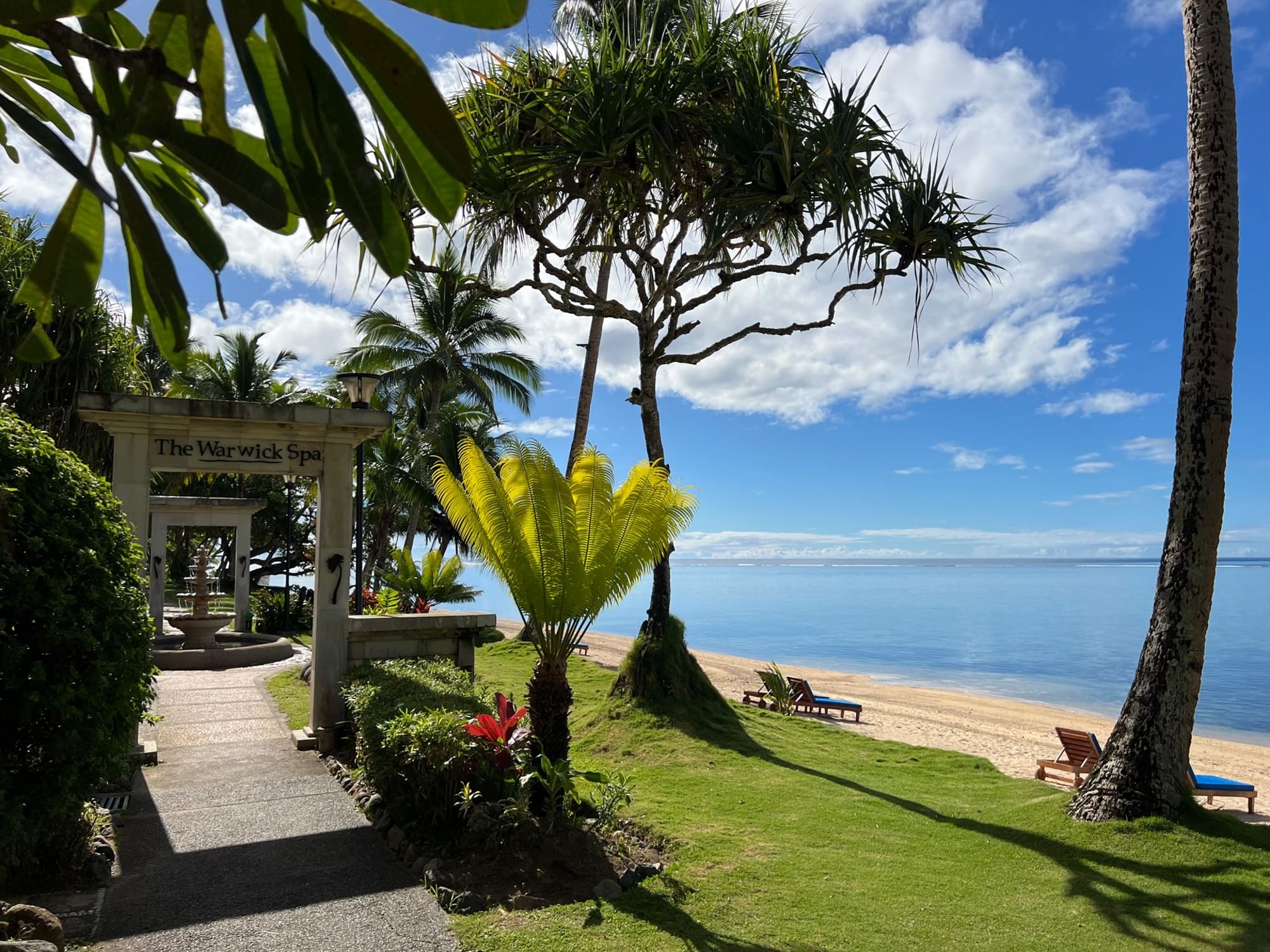Pathway leading to Warwick Spa with tropical plants and beach view at Warwick Fiji Resort and Spa
