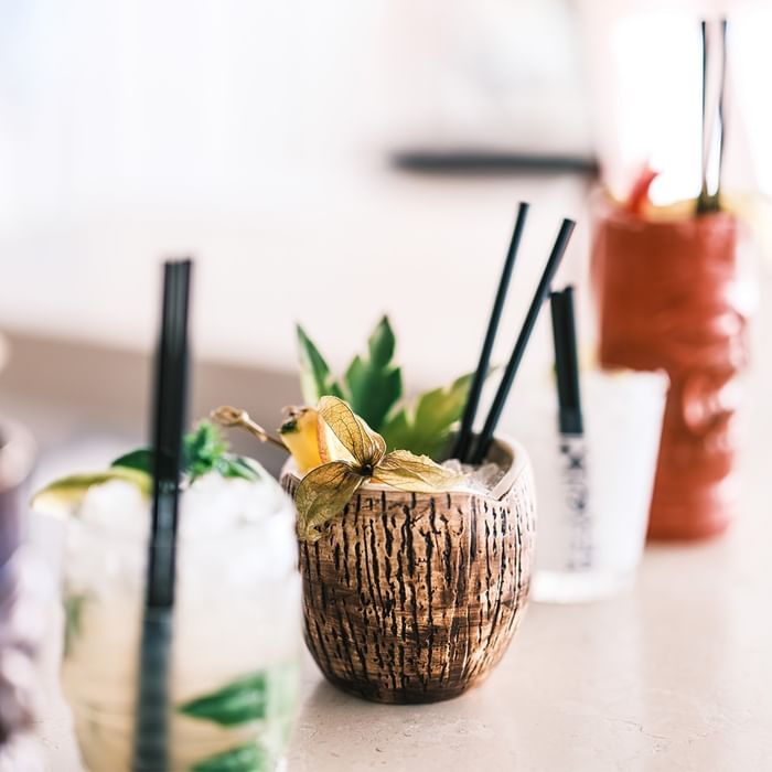 Cocktail tropicali con cannucce in bicchieri di cocco a tema Tiki al Falkensteiner Hotel & Spa Jesolo