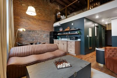 One Bedroom King Suite with Loft interior with brick wall, kitchenette and mezzanine level at The Delegate Hotel