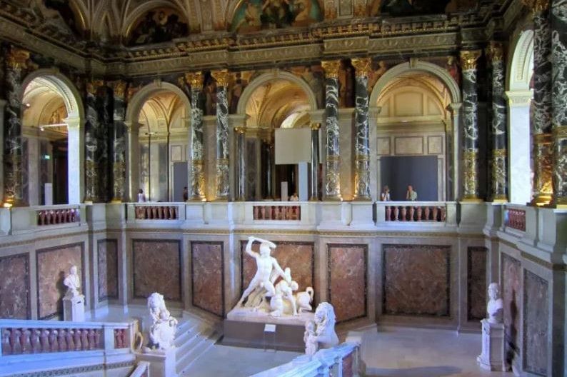 Ornate interior of the Kunsthistorisches Museum featuring its grand staircase hall, marble columns, and classical sculptures
