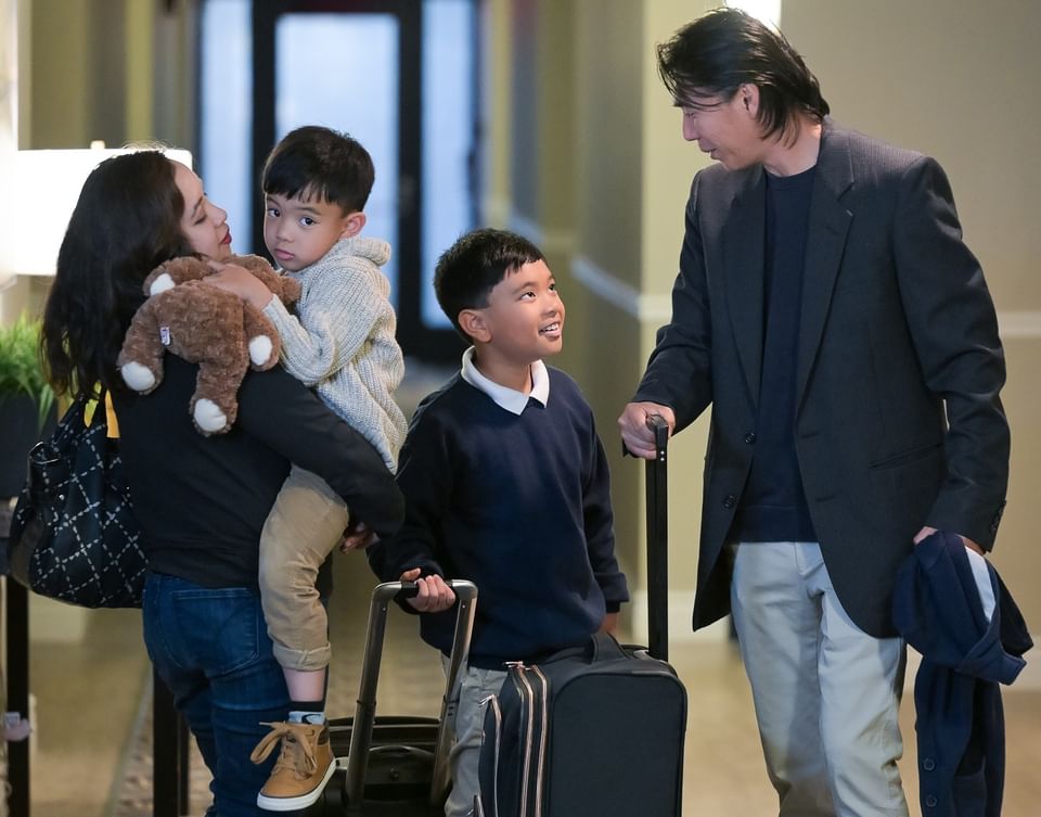 Family with two children walking down a hotel hallway with rolling suitcases and a teddy bear at Rodd Grand Yarmouth