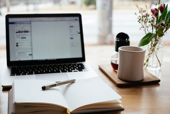 Closeup of a desk with laptop, tea & notebook at Amara Hotels