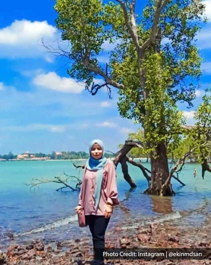 a girl standing in front of a tree