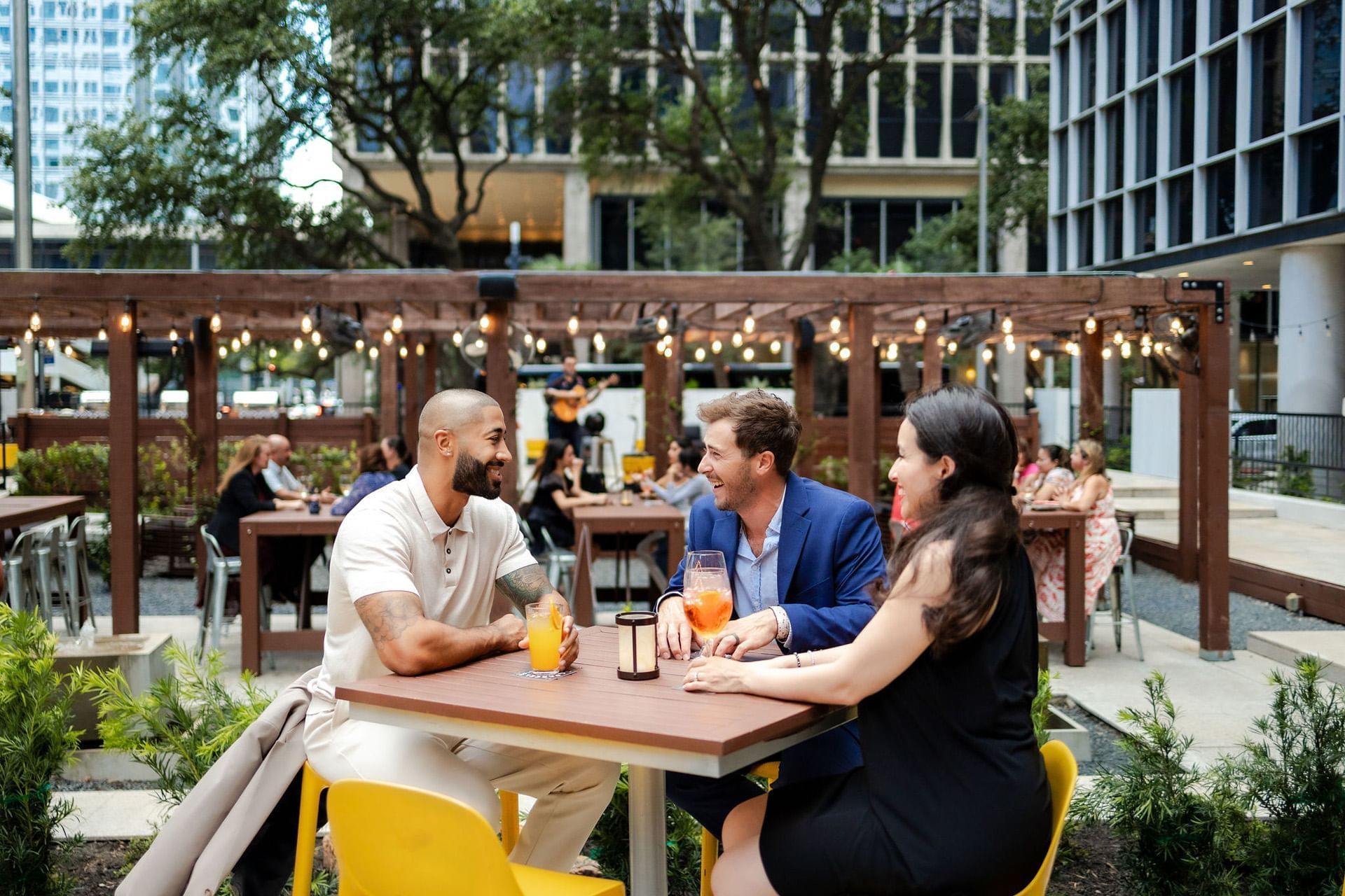 A group of people sitting at tables in an outdoor seating area.