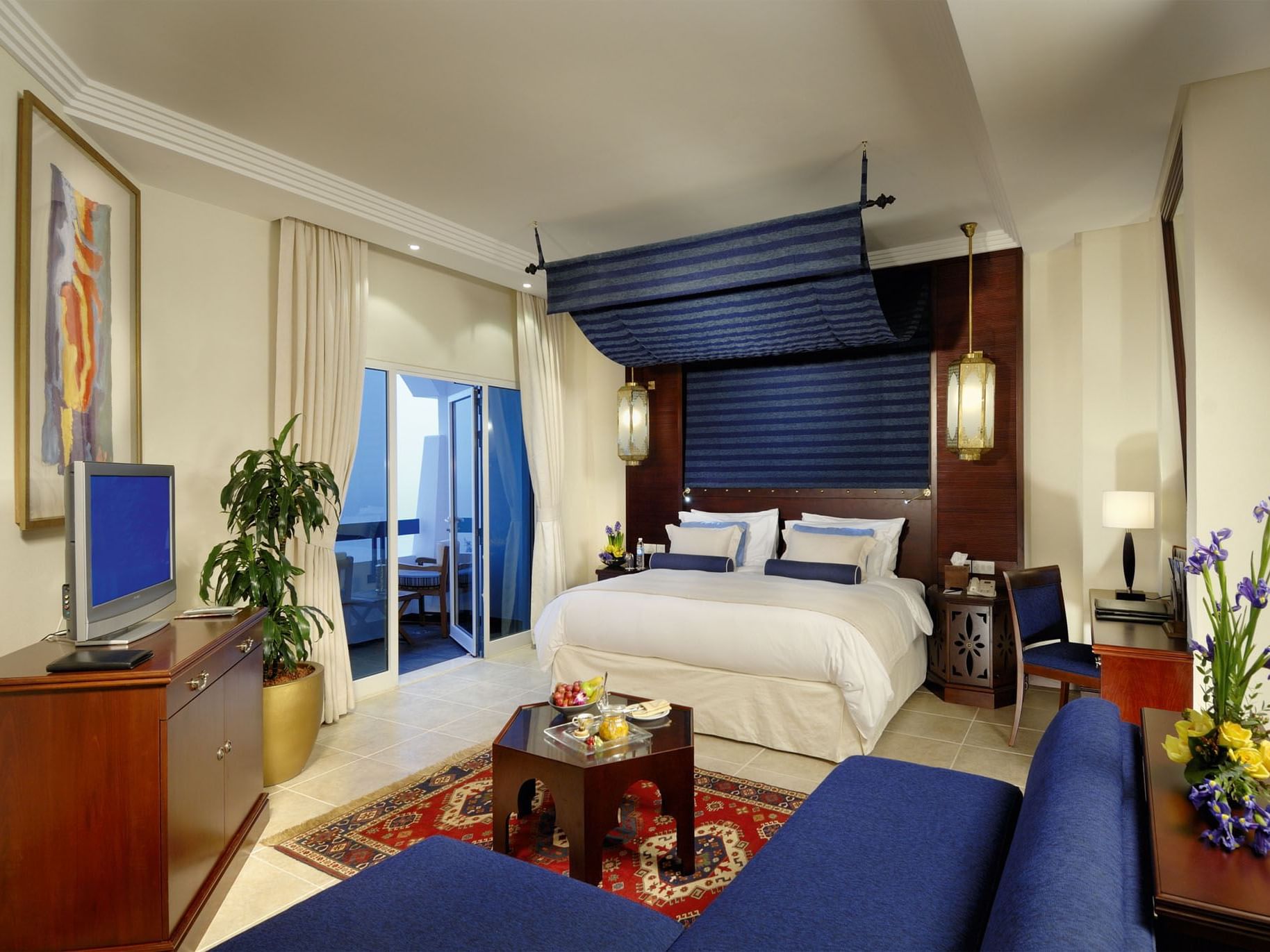 A king bed with a TV in Sea View Junior Suites at Ajman Hotel