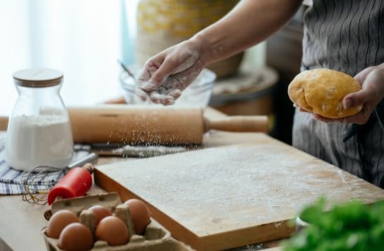 Close-up of man sprinkling flour on a board in the kitchen at Porta Hotel del Lago