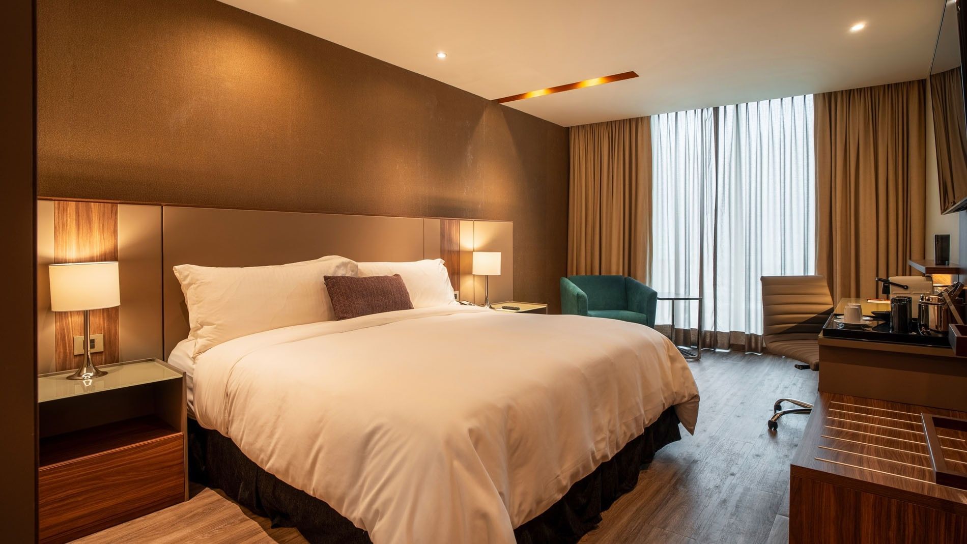 King Deluxe with a king-size bed, warm lighting, and a teal armchair at Camino Real Fashion Drive, Monterrey