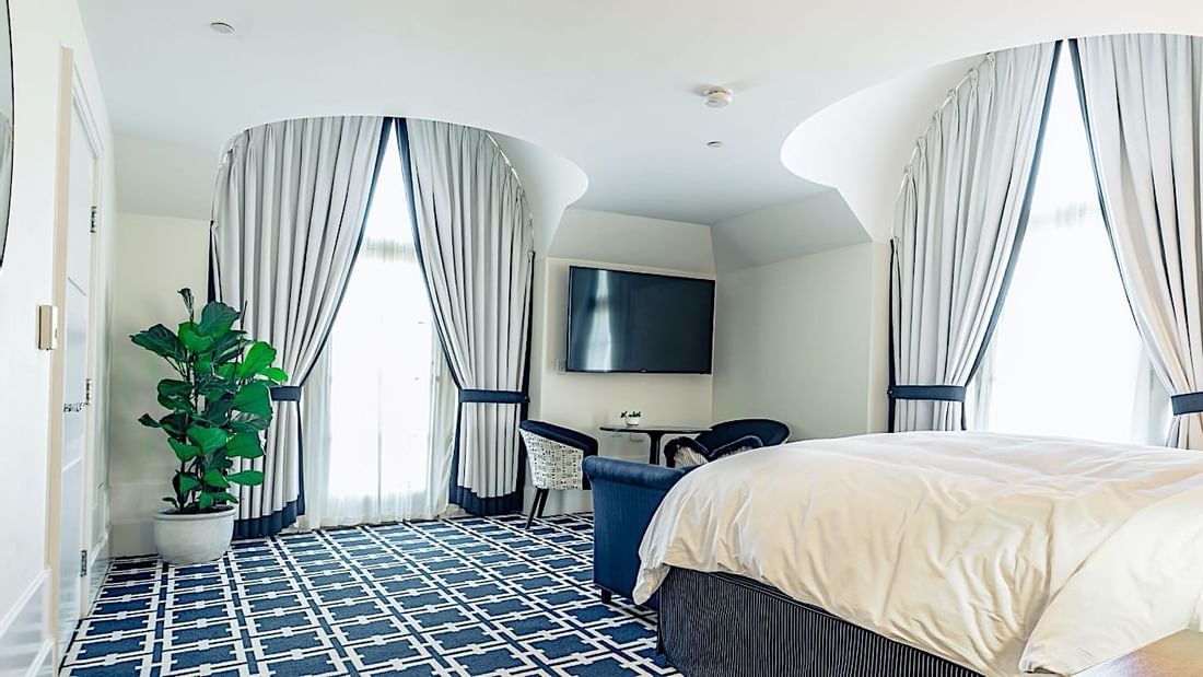 Grand Deluxe Suite featuring a large bed, stylish curtains, and a distinctive patterned carpet at El Prado Hotel