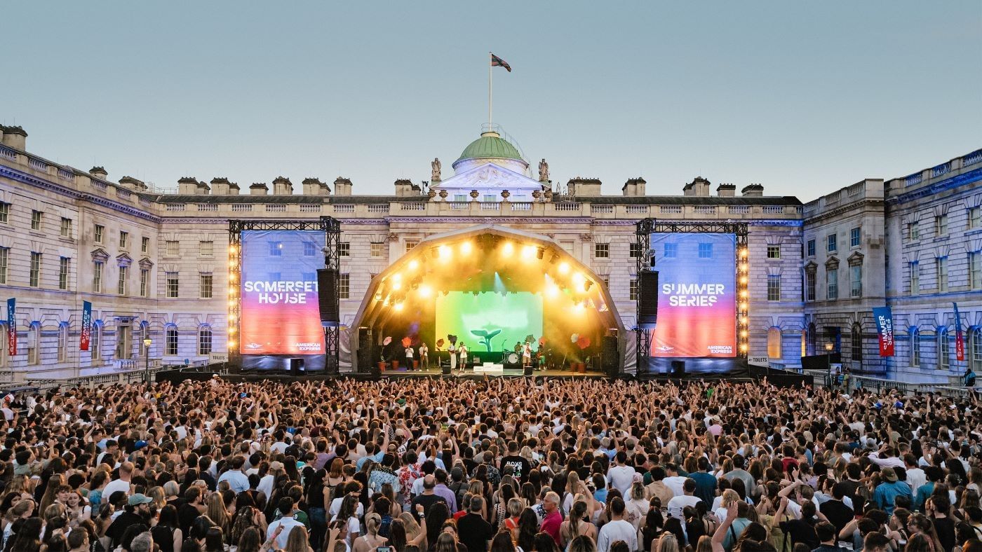 Outdoor summer concert at Somerset House near The Londoner Hotel, with a large crowd gathered before a lit stage