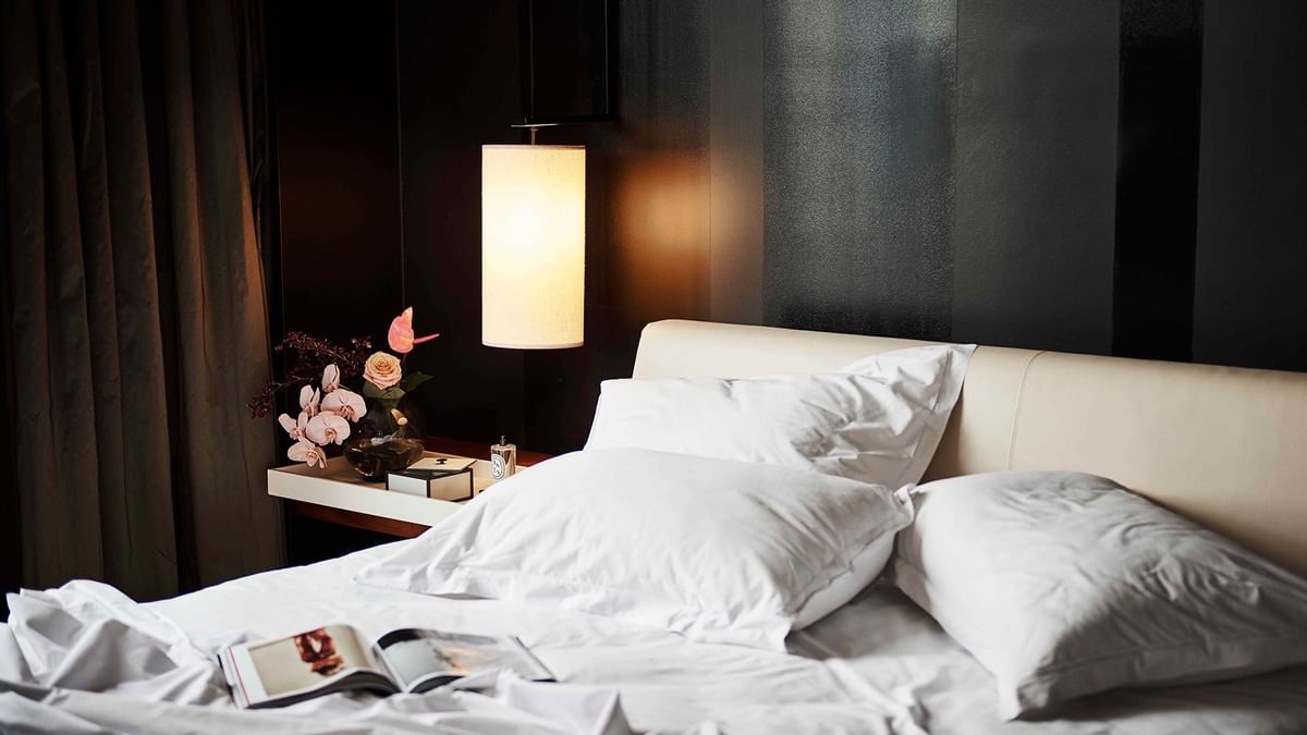 Magazine, messy bed, lamp & nightstand at Crown Hotels