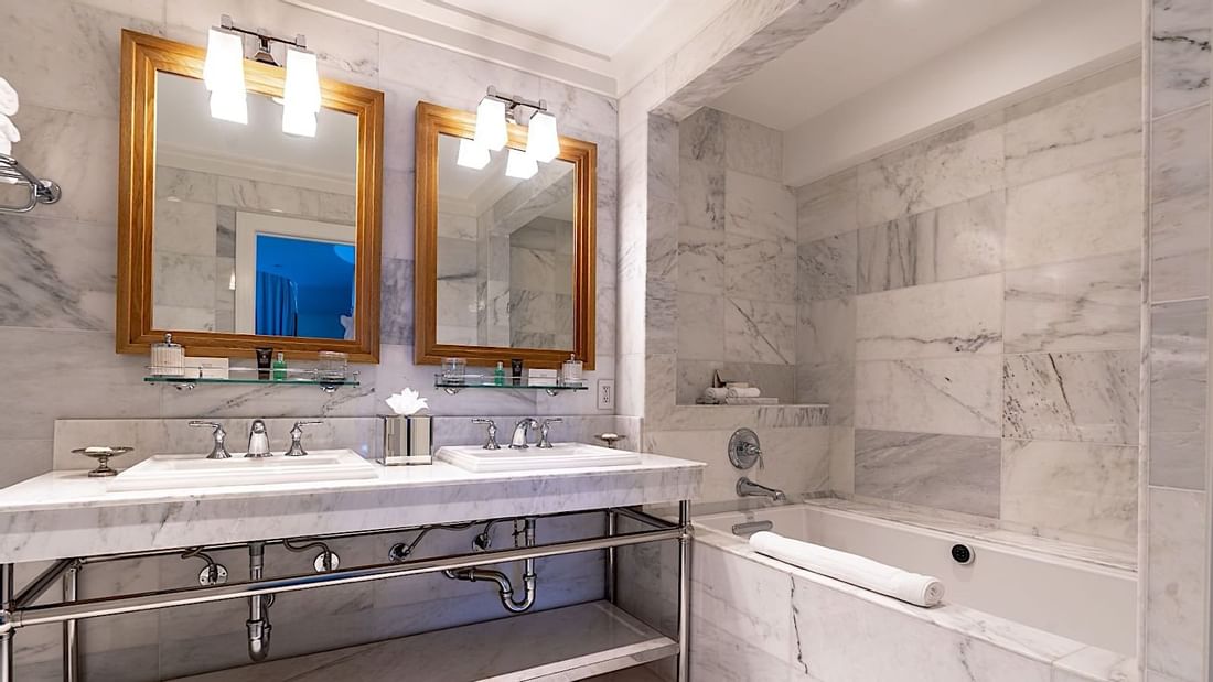 Double vanity, elegant mirrors, and a deep soaking bathtub in Grand Deluxe Suite at El Prado Hotel