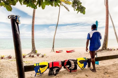 Local man holding a paddle by the beach at Tambua Sands Beach Resort