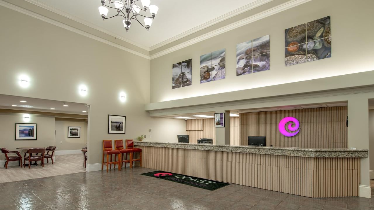 Spacious hotel lobby with modern reception desk, seating area, and nature photography at Coast Edson Hotel.
