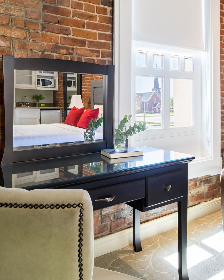 mirrored desk with chair near big window with exposed brick