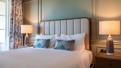 King bed with a cushioned headboard & bed lamps in Junior Golf Suite at Camp Creek Inn