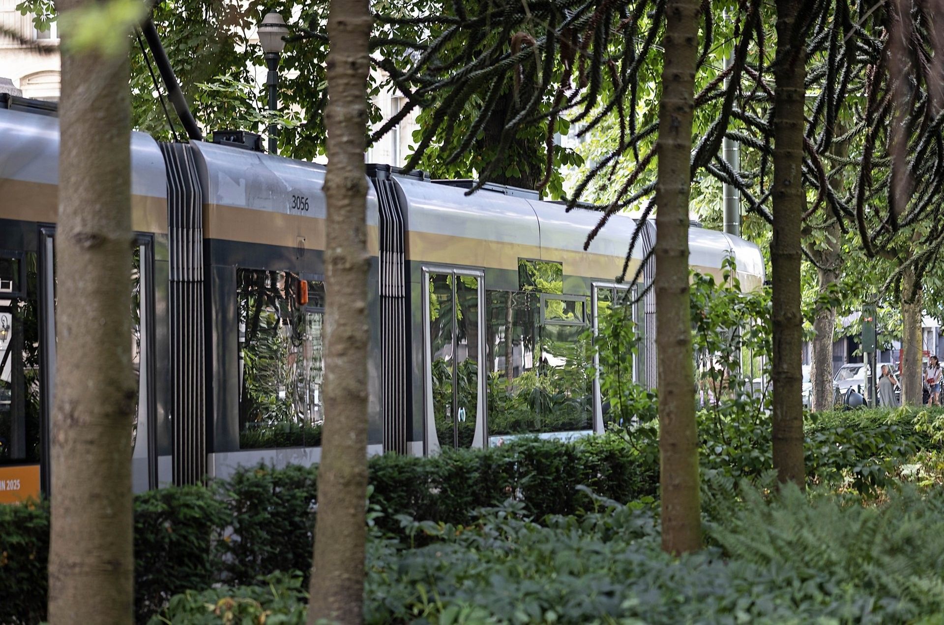 Tram 3056 moving past leafy bushes and trees at Hotel Barsey by Warwick Bruxelles 