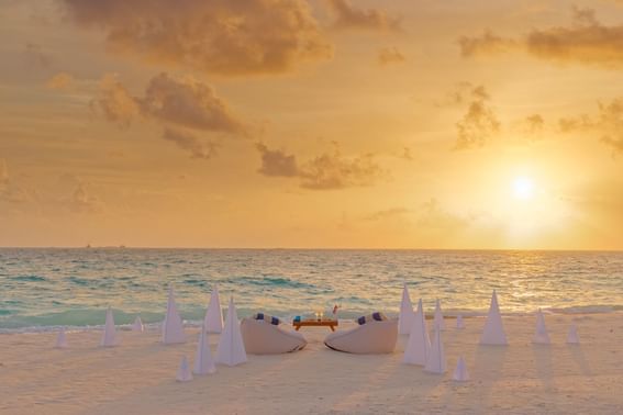 A beach setting for a romantic dinner at sunset, with a table near Grand Park Kodhipparu, Maldives