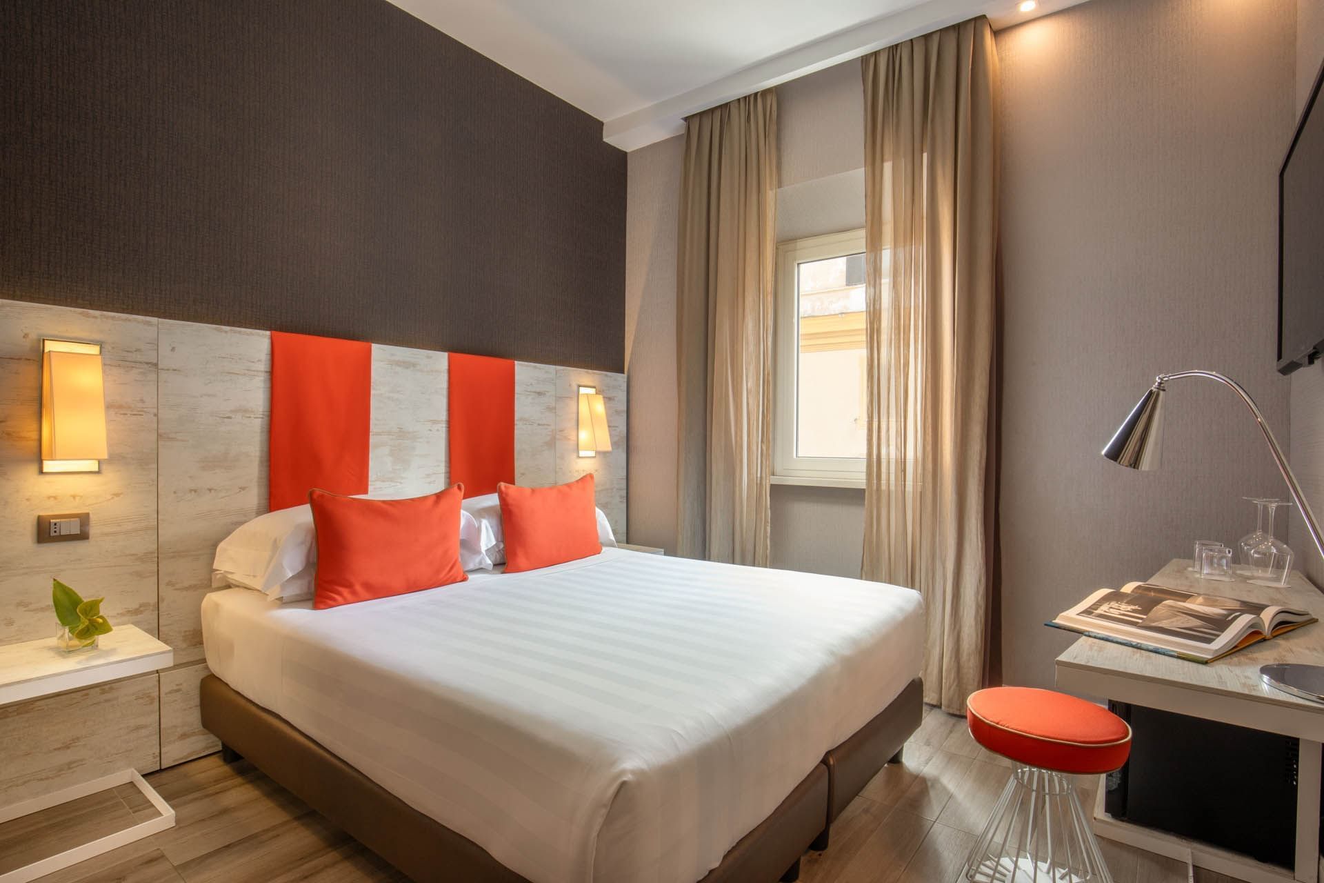 Modern Classic Room at The Guardian Hotel with a double bed, orange pillows, warm lighting, and stylish decor