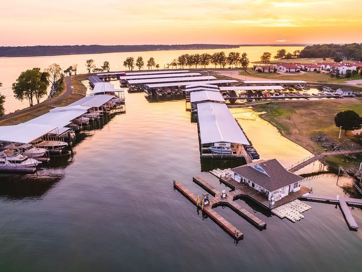 Aerial view of a large marina with covered slips on a calm lake during a golden sunset at Shangri-La Resort and Golf Club