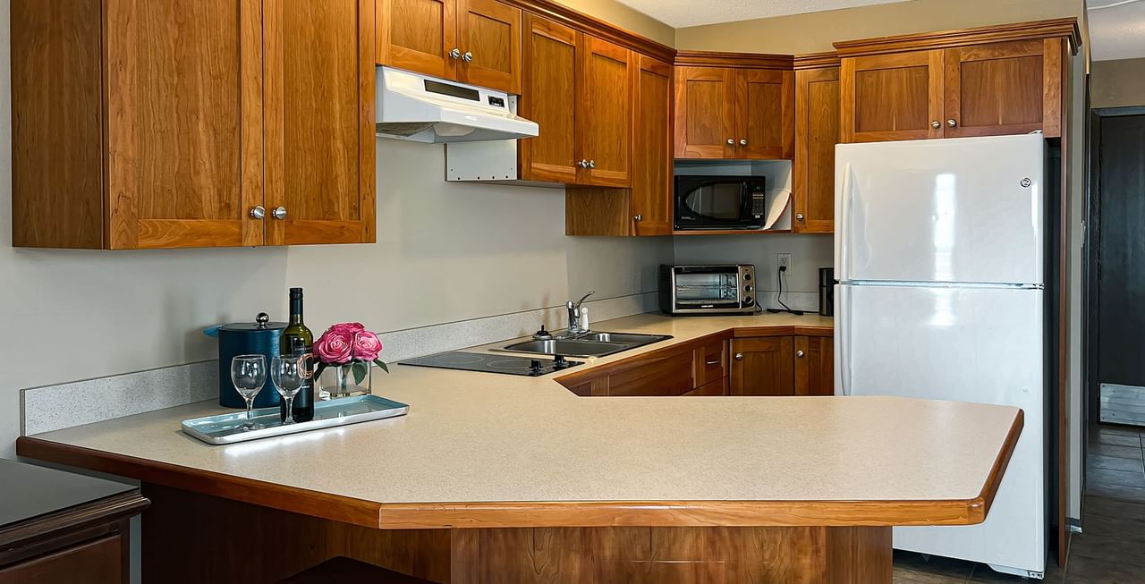 Kitchen with fridge, microwave, sink, wine, and flower
