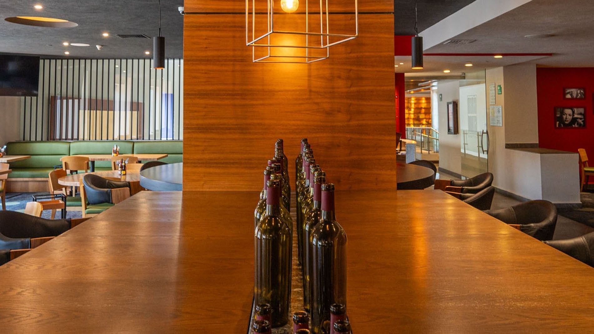 Rows of wine bottles on a wooden table in Maria Bonita featuring a modern wood pillar and bar at Camino Real Pedregal Mexico