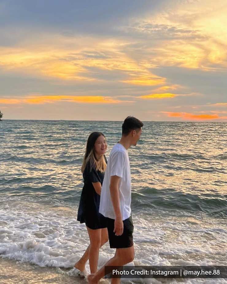 couple walking hand in hand on beach at sunset