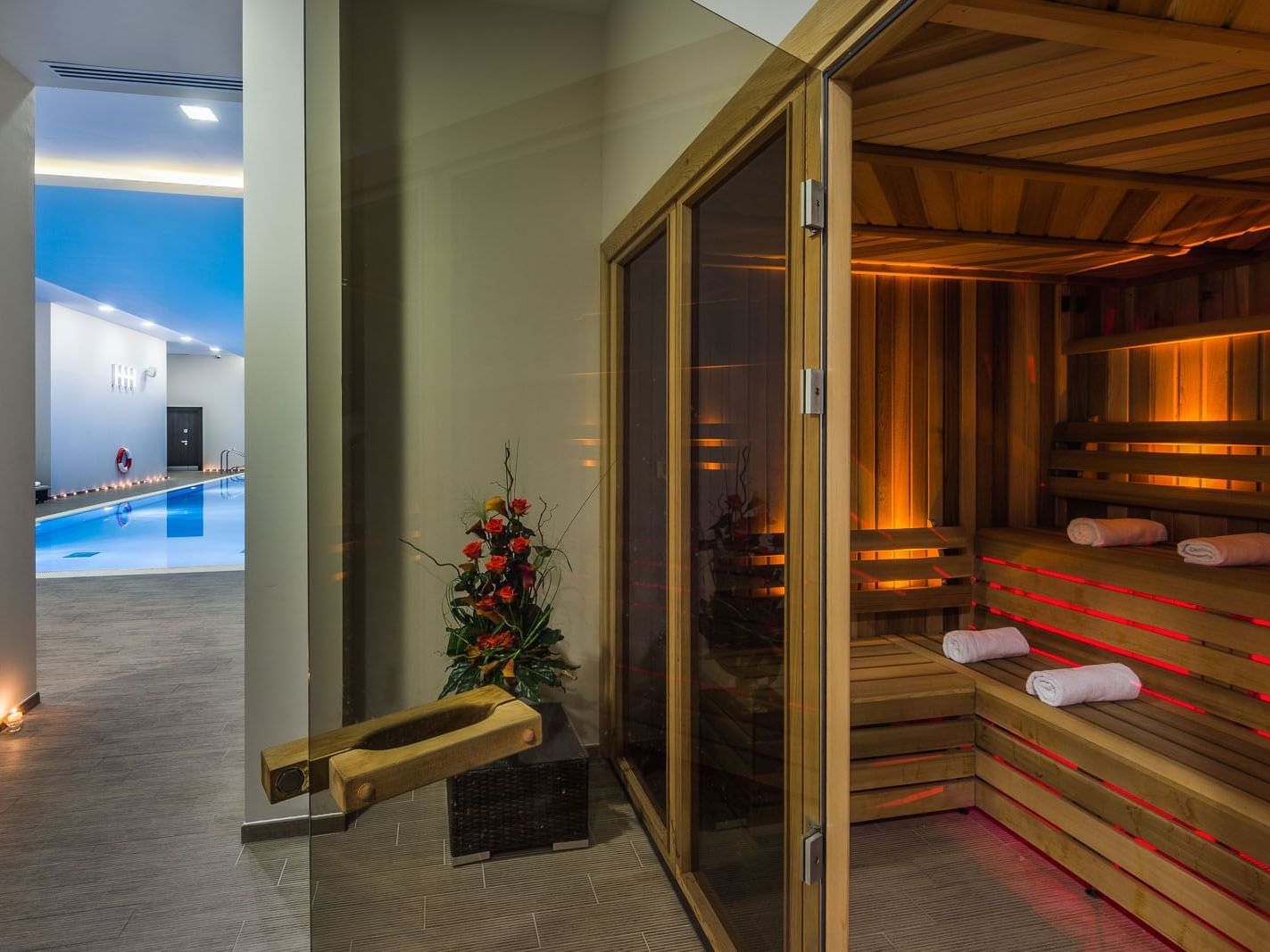 Wooden sauna with warm light and towels beside an indoor heated pool in a spa at Heston Hyde Hotel