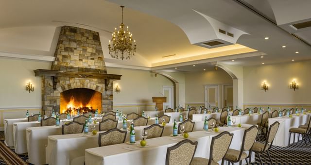 Classroom tables with apples by a stone fireplace under a chandelier in Roosevelt Room at Mountain View Grand Resort & Spa