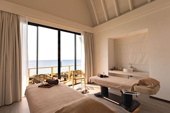 Peaceful Kandu Spa room at Ananea Madivaru Maldives with two treatment tables, offering ocean views through large windows