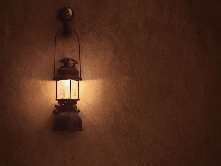 Illuminated vintage wall lantern on a textured dark wall casting a soft glow at Al Fahidi near DAMAC Hotels & Resorts