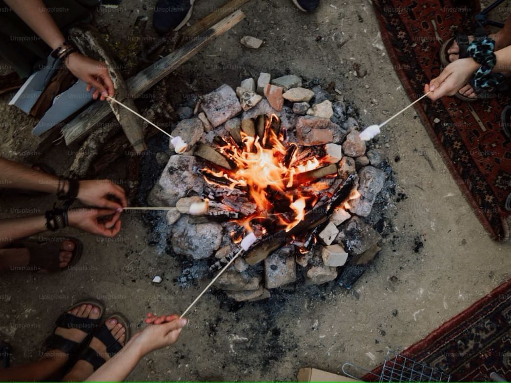 a bonfire with people making s'mores around the fire