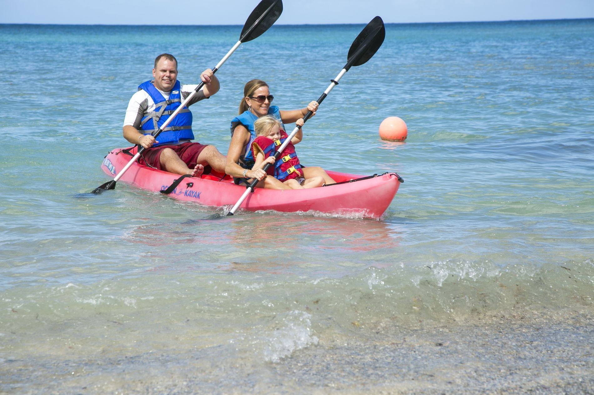 Closeup on a family kayaking at the ocean near Buccaneer Hotel
