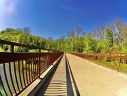 Scenic view of a bridge extending over the river, surrounded by lush greenery at Felderman Park near Off Shore Resort
