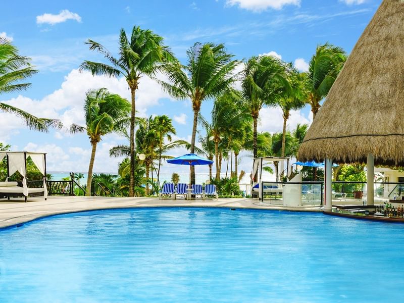An outdoor pool area with sunbeds at The Reef Playacar