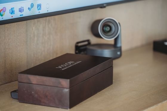 A Vision box and a webcam are placed on a shelf below a monitor displaying icons.