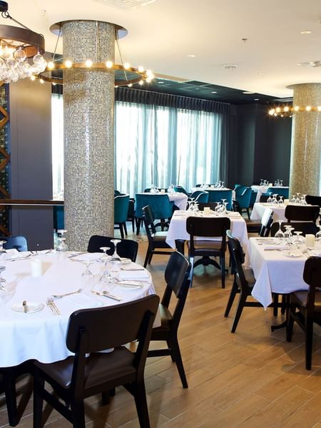 Abbiocco with white-clothed tables by mosaic pillars under glass chandeliers at Warwick Paradise Island Bahamas