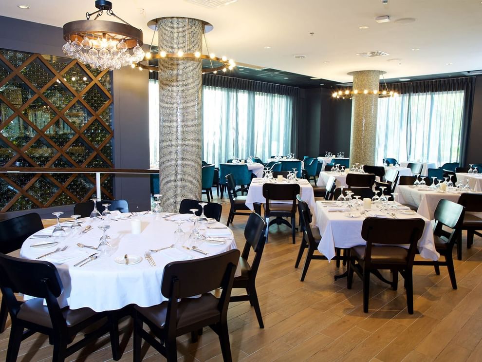 Abbiocco with white-clothed tables by mosaic pillars under glass chandeliers at Warwick Paradise Island Bahamas