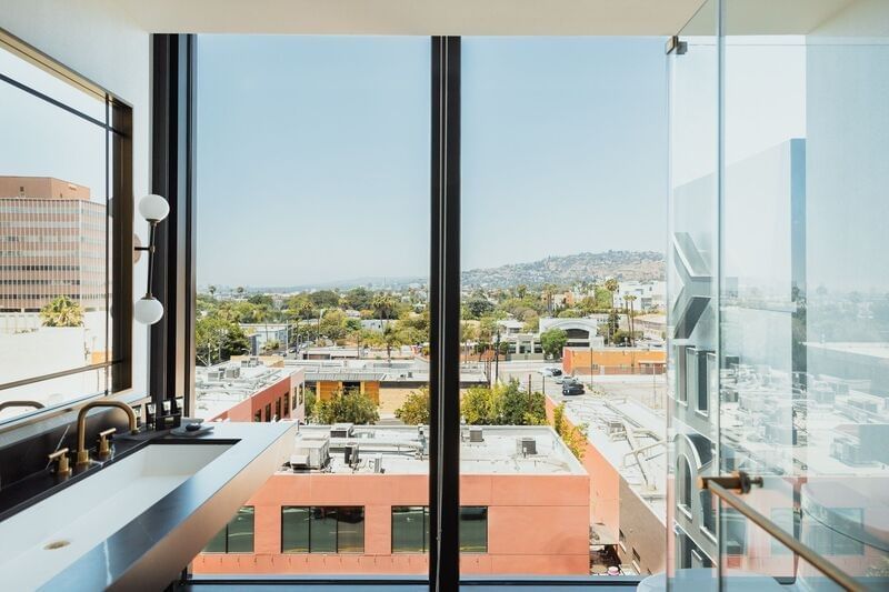A bathroom with a sink and shower, looking out onto a city view