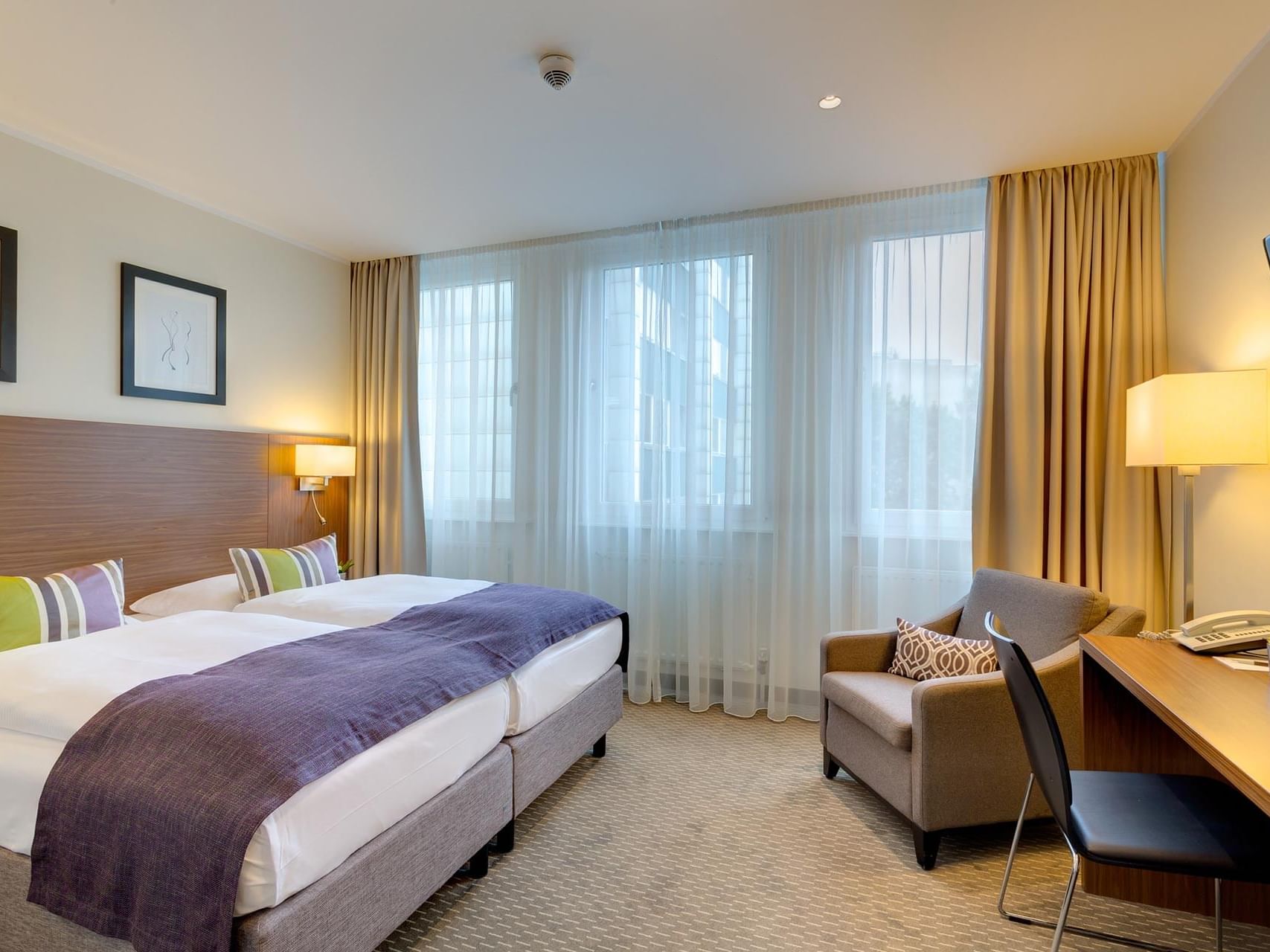 An elegant guest room in neutral tones with large windows at Hotel Sylter Hof Berlin.