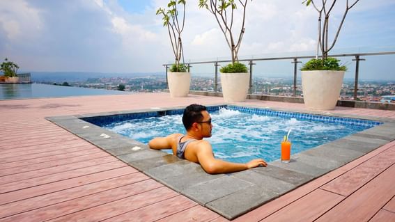 Man relaxing in jacuzzi while having a fresh juice at LK Pandanaran Hotel & Serviced Apartments