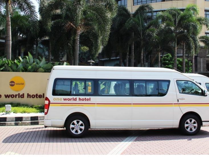 White shuttle service van parked in front of the hotel entrance at One World Hotel