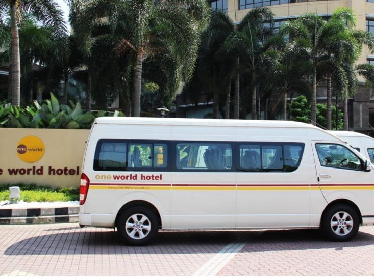 A shuttle service van parked in front of the hotel entrance at One World Hotel