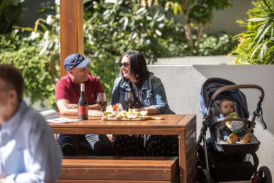 People hanging out in the outdoor BBQ area with arranged wooden seats at Alcyone Hotel Residences