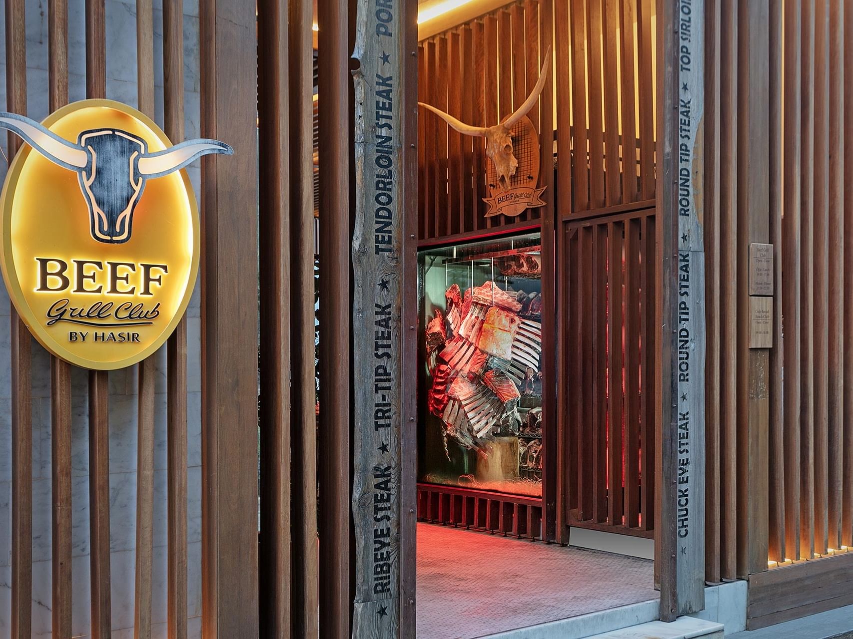 Entrance view of Et Grill Club with a wooden door, a bull head, and a menu board.